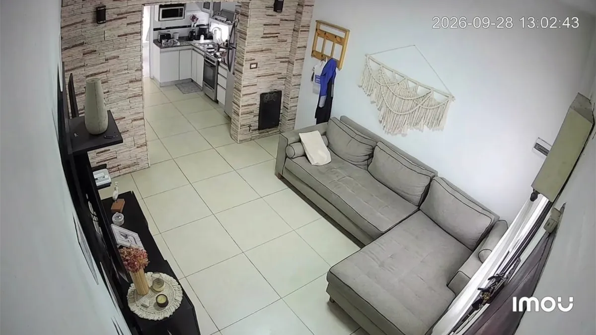 Captura de la app Imou: imagen gran angular de un living con sillón y cocina al fondo